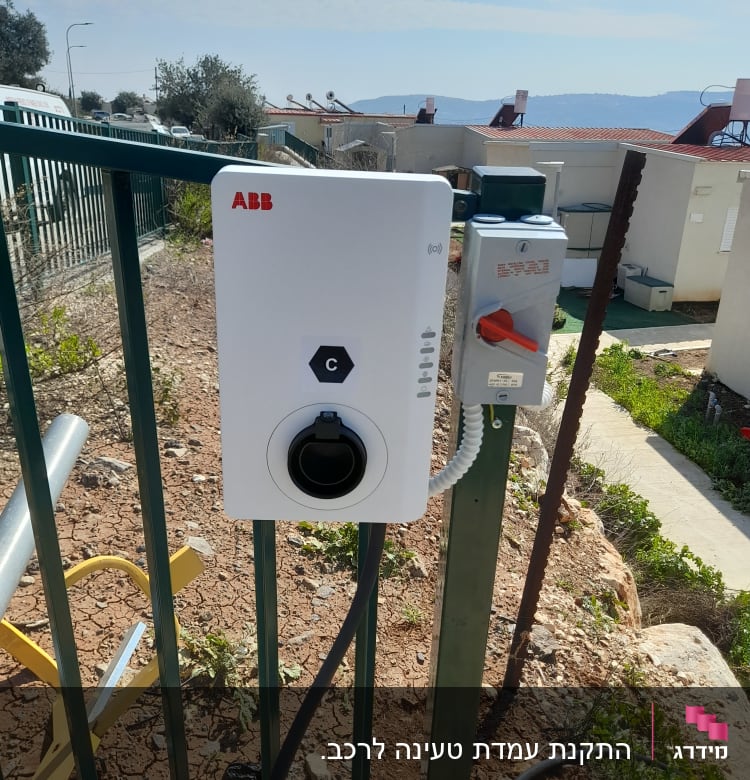 עמדת טעינה חשמלית עם כבל מחובר לגדר